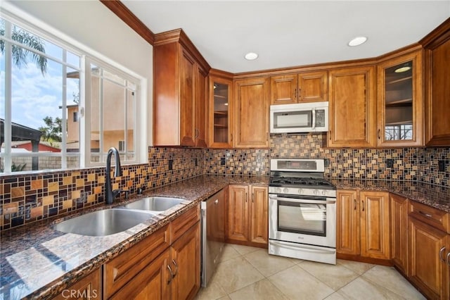 kitchen featuring appliances with stainless steel finishes, sink, decorative backsplash, and dark stone counters