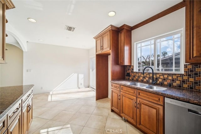 kitchen featuring tasteful backsplash, sink, dark stone counters, stainless steel dishwasher, and light tile patterned floors