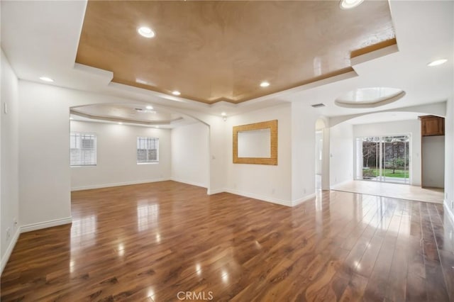 empty room with a tray ceiling and dark hardwood / wood-style flooring