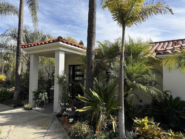 exterior space featuring a tiled roof and stucco siding