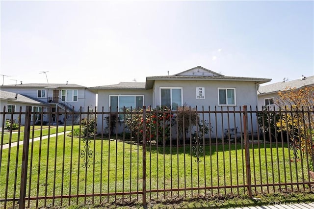 view of front facade featuring fence, a front lawn, and stucco siding