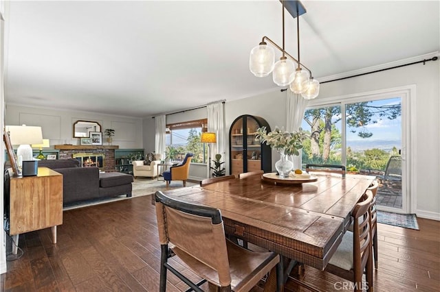 dining space with a brick fireplace and dark wood-type flooring