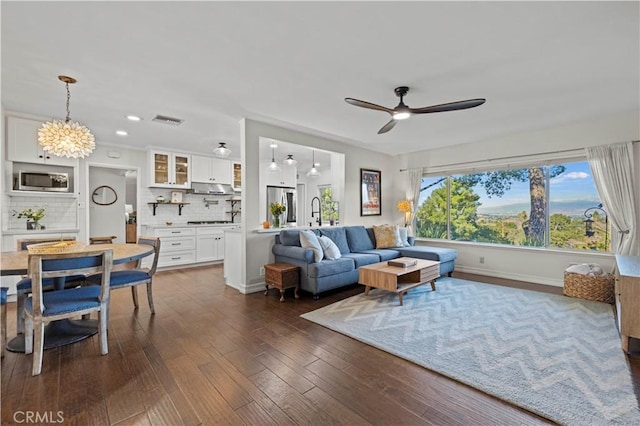 living room with sink, dark wood-type flooring, and ceiling fan with notable chandelier