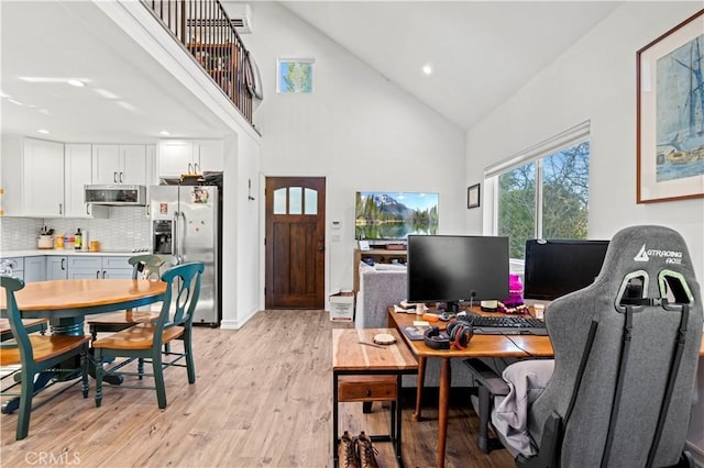 office area with high vaulted ceiling and light hardwood / wood-style flooring