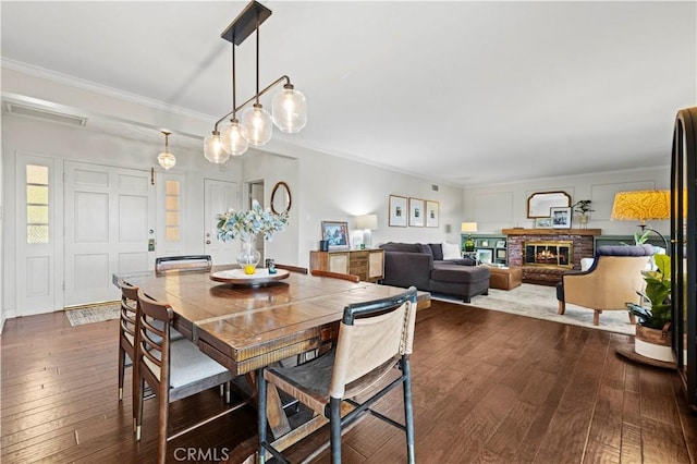 dining room featuring crown molding, dark hardwood / wood-style floors, and a fireplace