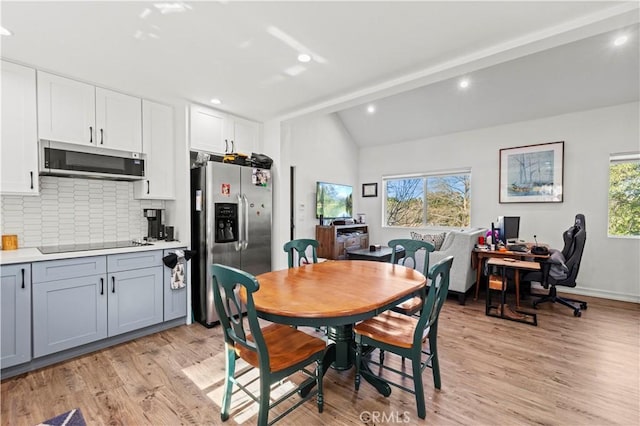 dining space featuring lofted ceiling with beams and light wood-type flooring