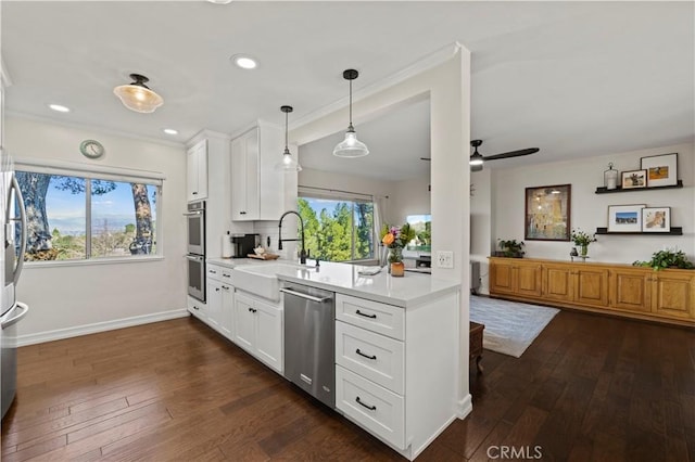 kitchen featuring pendant lighting, sink, dark wood-type flooring, appliances with stainless steel finishes, and white cabinets