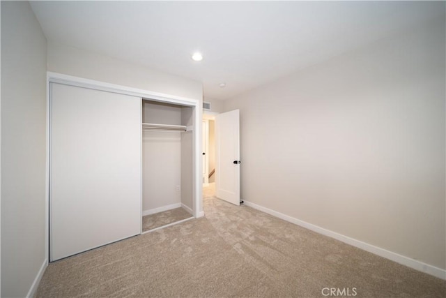 unfurnished bedroom with recessed lighting, light carpet, visible vents, baseboards, and a closet