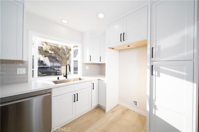 kitchen with light countertops, a sink, stainless steel dishwasher, and white cabinetry