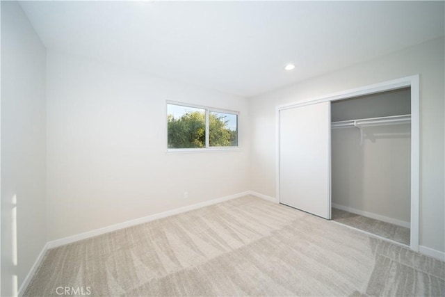 unfurnished bedroom with recessed lighting, baseboards, a closet, and light colored carpet