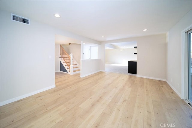 spare room with light wood finished floors, baseboards, visible vents, stairway, and recessed lighting