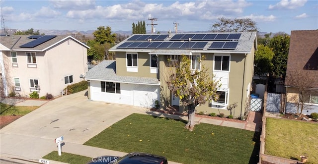 view of front of home with a shingled roof, a front yard, stucco siding, and solar panels