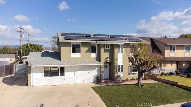 view of front facade featuring solar panels, brick siding, fence, stucco siding, and a front yard