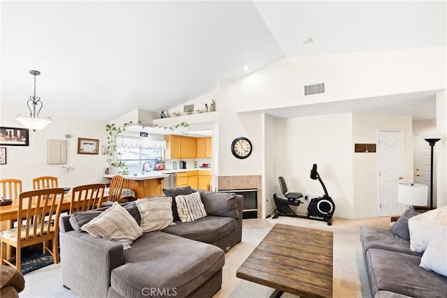 carpeted living room featuring high vaulted ceiling, a tiled fireplace, and sink