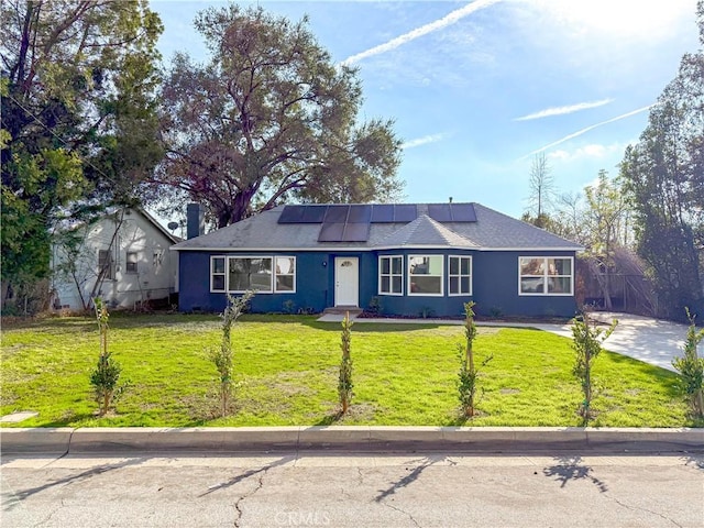 single story home featuring a front yard and solar panels