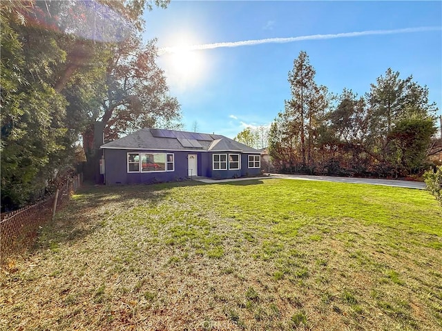 ranch-style house featuring a front lawn and solar panels