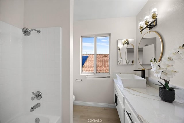 bathroom featuring toilet, shower / bath combination, wood finished floors, vanity, and baseboards