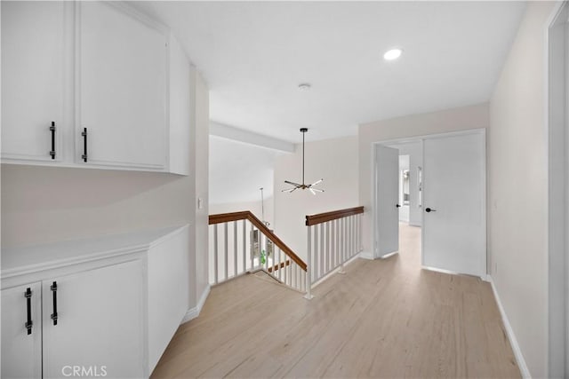 corridor with light wood-style flooring, recessed lighting, an upstairs landing, baseboards, and vaulted ceiling