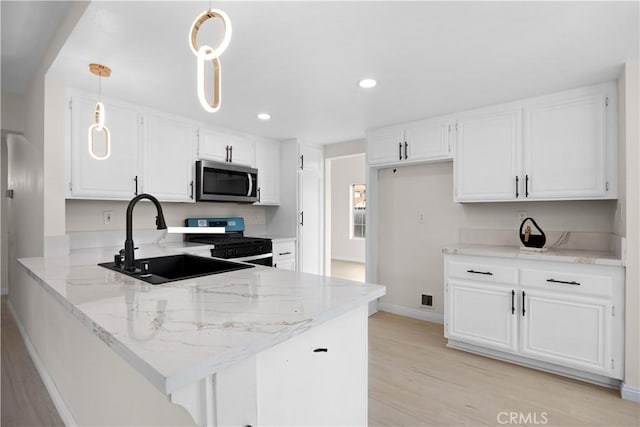 kitchen with stainless steel microwave, a peninsula, white cabinets, hanging light fixtures, and gas range oven