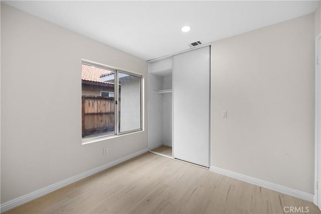 unfurnished bedroom with light wood-style flooring, a closet, visible vents, and baseboards