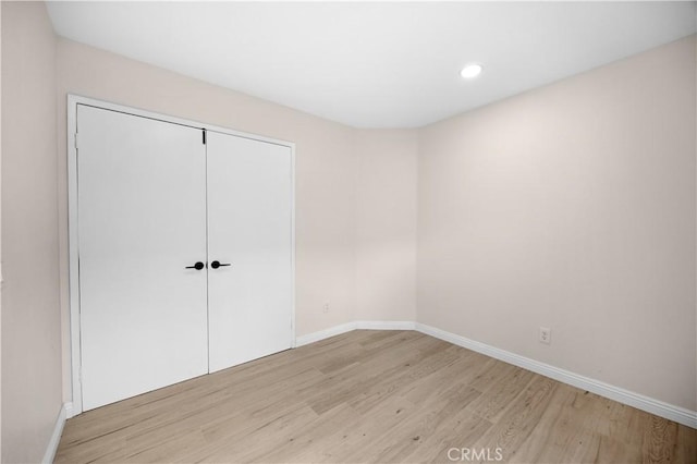 unfurnished bedroom featuring light wood-style flooring, baseboards, a closet, and recessed lighting