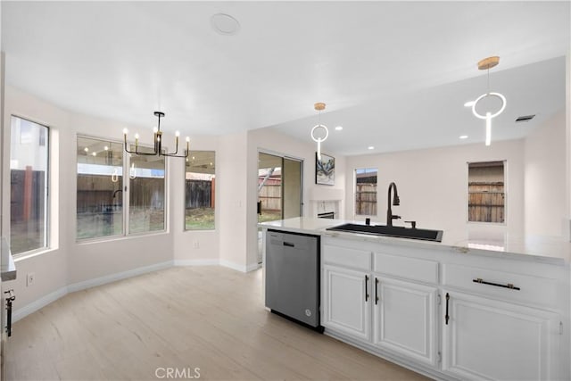 kitchen with hanging light fixtures, stainless steel dishwasher, a sink, and white cabinetry