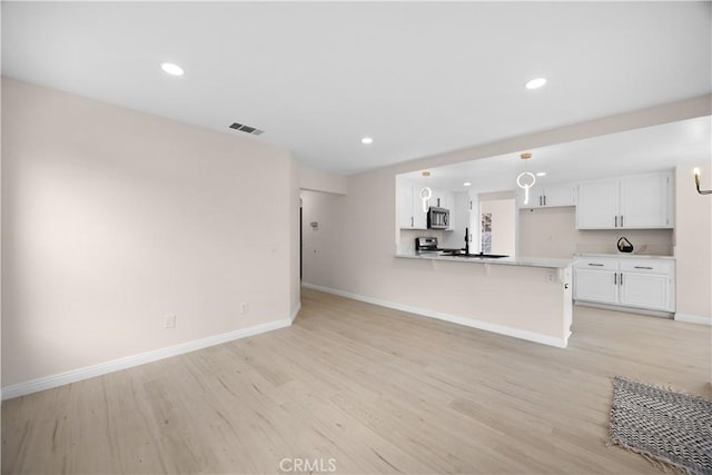 kitchen featuring visible vents, white cabinets, appliances with stainless steel finishes, open floor plan, and decorative light fixtures