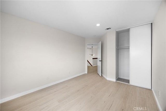 unfurnished bedroom featuring light wood-style floors, a closet, visible vents, and baseboards