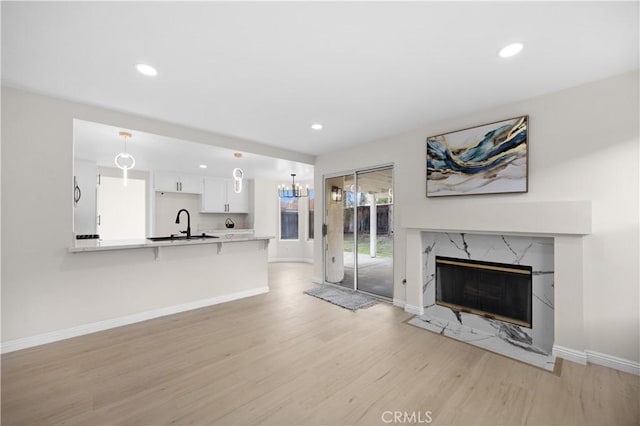 unfurnished living room featuring light wood-style flooring, a premium fireplace, baseboards, and recessed lighting