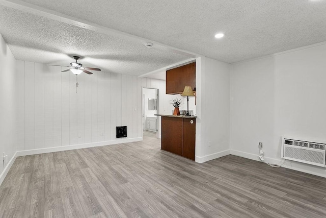 unfurnished living room featuring hardwood / wood-style flooring, ceiling fan, a textured ceiling, and an AC wall unit