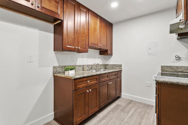 kitchen with stone countertops, light hardwood / wood-style floors, and sink