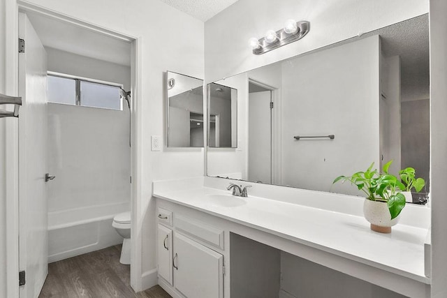 full bathroom featuring hardwood / wood-style flooring, vanity, toilet, tub / shower combination, and a textured ceiling