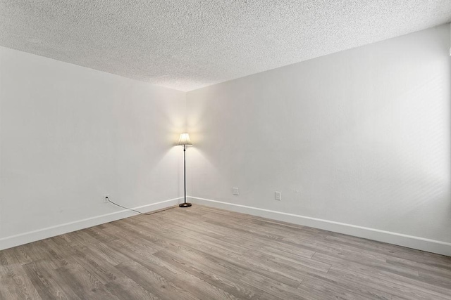 spare room featuring light hardwood / wood-style floors and a textured ceiling