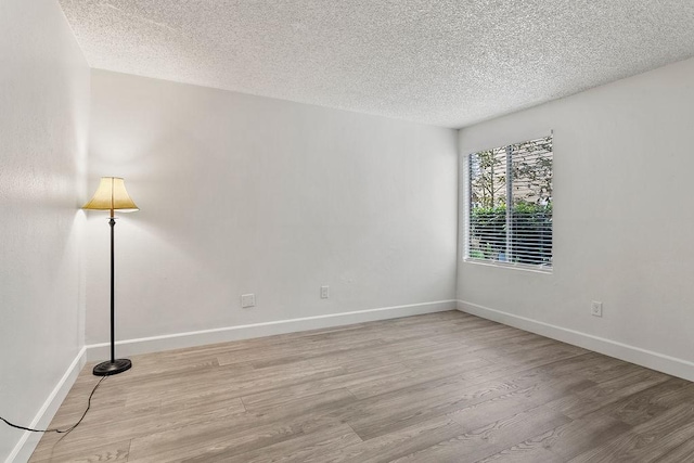 unfurnished room with a textured ceiling and light hardwood / wood-style floors