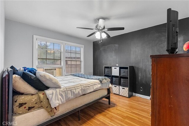 bedroom featuring cooling unit, hardwood / wood-style floors, and ceiling fan