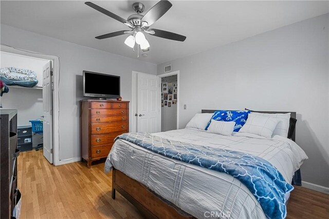 bedroom featuring ceiling fan, a walk in closet, hardwood / wood-style floors, and a closet