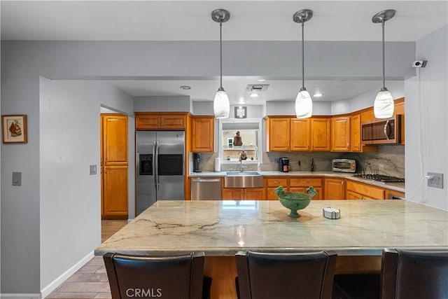 kitchen featuring sink, appliances with stainless steel finishes, backsplash, a kitchen breakfast bar, and light stone counters