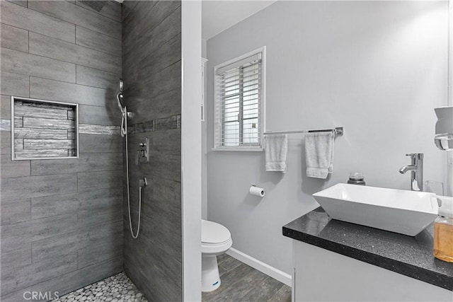 bathroom with vanity, hardwood / wood-style flooring, toilet, and tiled shower