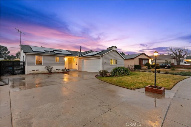 ranch-style house featuring a yard, a garage, and solar panels