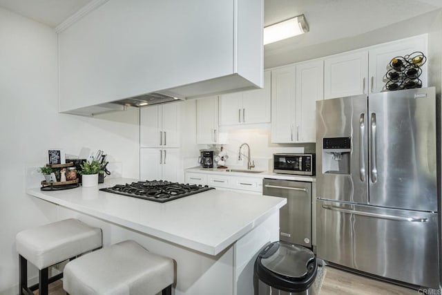 kitchen with sink, a breakfast bar area, white cabinets, kitchen peninsula, and stainless steel appliances