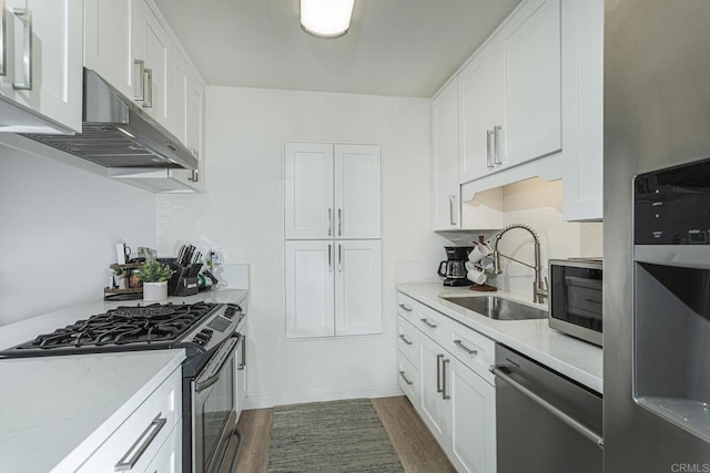 kitchen featuring sink, stainless steel appliances, dark hardwood / wood-style floors, light stone counters, and white cabinets