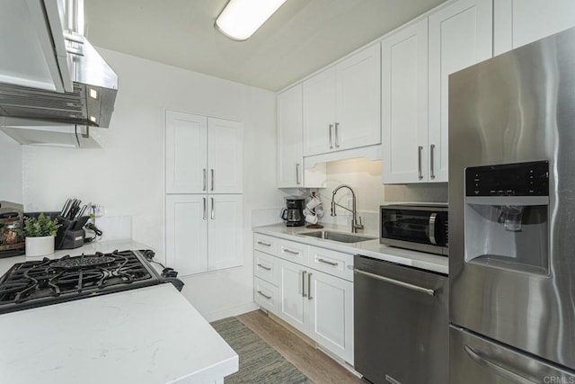 kitchen with sink, white cabinetry, stainless steel appliances, dark hardwood / wood-style floors, and light stone counters