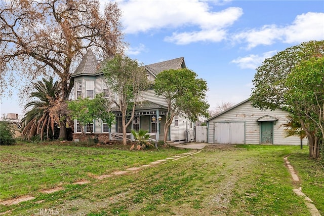 victorian-style house featuring an outdoor structure and a front yard