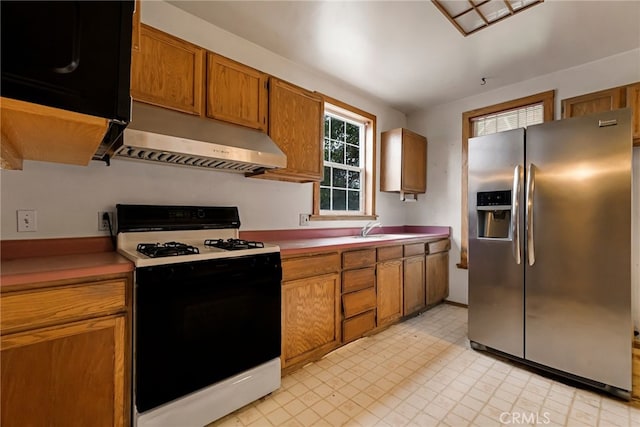 kitchen featuring stainless steel fridge, gas range oven, and sink
