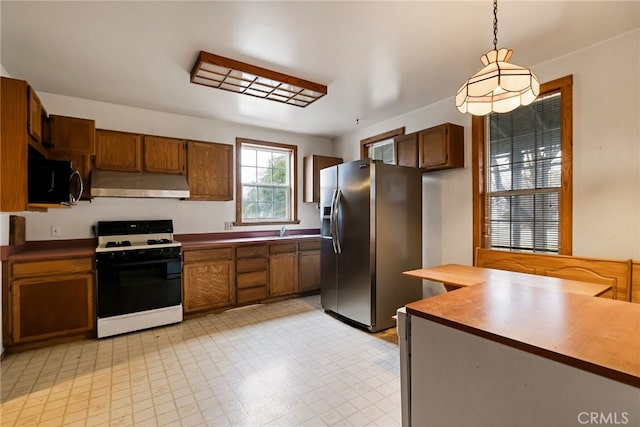 kitchen with hanging light fixtures, stainless steel refrigerator with ice dispenser, sink, and range with gas cooktop