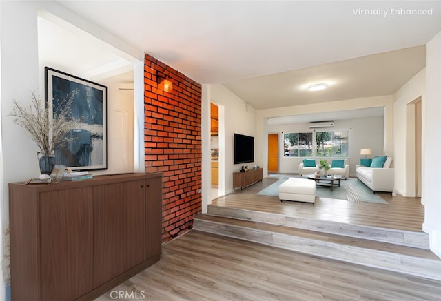 living area featuring brick wall, a wall mounted AC, and wood finished floors