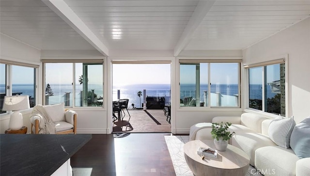 sunroom / solarium featuring beam ceiling and a water view