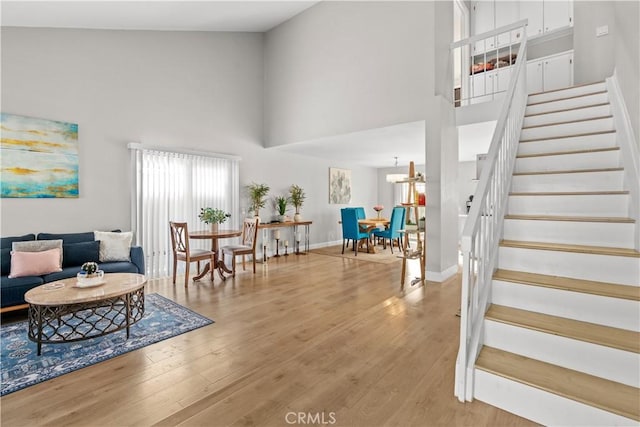 living room featuring a notable chandelier, light hardwood / wood-style floors, and a high ceiling