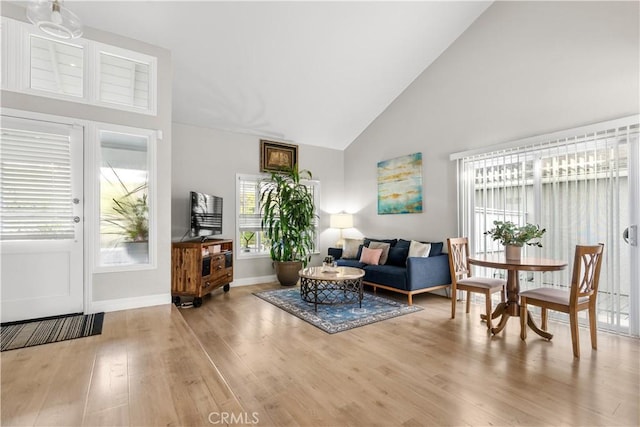 living room with high vaulted ceiling and light hardwood / wood-style flooring