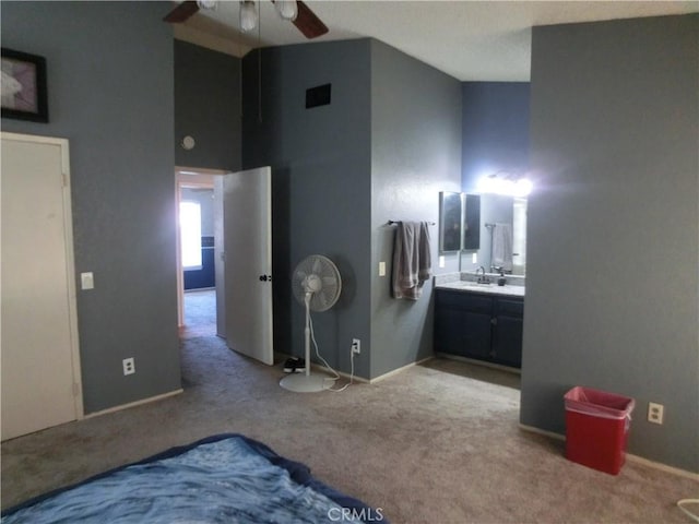 carpeted bedroom with visible vents, connected bathroom, a sink, high vaulted ceiling, and baseboards